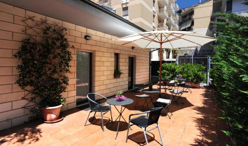 un patio con mesas, sillas y una sombrilla en Villa Santacroce, en San Giovanni Rotondo