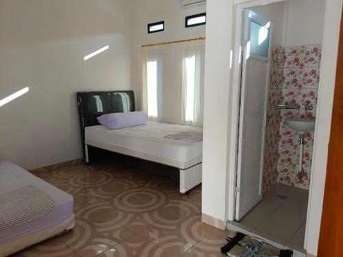 a small room with a bed and a shower at Sibento Komodo Homestay in Labuan Bajo
