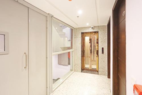 un pasillo con paredes blancas y una puerta de cristal en Frankstay By Hotel Mayfair Residency en Nueva Delhi