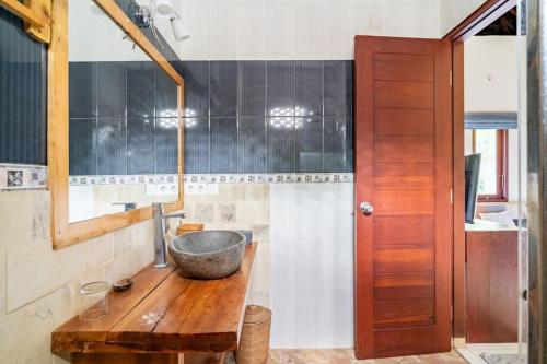 La salle de bains est pourvue d'un lavabo et d'un bol sur un comptoir en bois. dans l'établissement Villa Kenanga in Meninting By The Beach, à Mataram