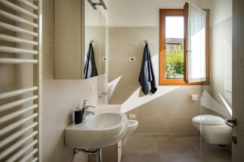 La salle de bains blanche est pourvue d'un lavabo et d'une fenêtre. dans l'établissement Appartamento Cansiglio, à Cappella Maggiore