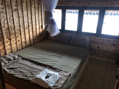 a small bed in a room with windows at Homestay Huyền Thoại Cao Nguyên Đá in Lao Ou Tchai