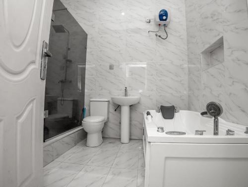 a white bathroom with a toilet and a sink at Luxury 4 bedroom duplex in Lekki