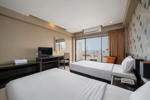 a hotel room with two beds and a desk at Welcome Plaza Hotel Pattaya in Pattaya Central