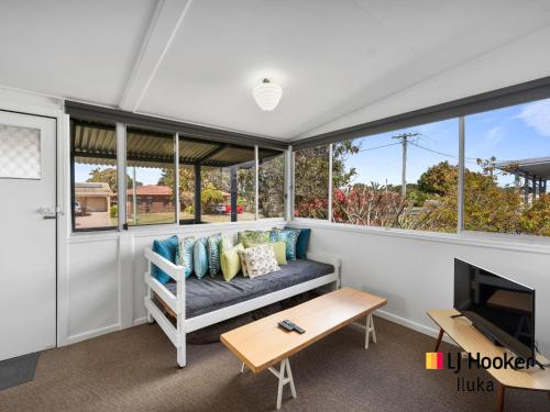 a screened in porch with a couch and a table at Fisherman's Cottage in Iluka