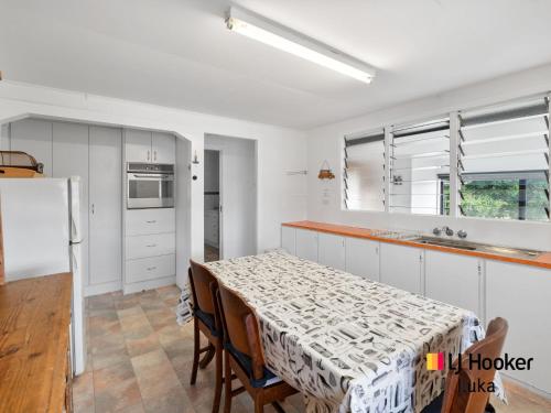 a kitchen with a table with chairs and a refrigerator at Fisherman's Cottage in Iluka