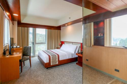 a hotel room with a bed and a desk and window at Sotogrande Hotel Baguio in Baguio