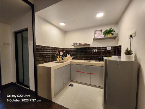una cocina con armarios blancos y una pared de azulejos negros en Dream Home (Marina View Villas), en Port Dickson