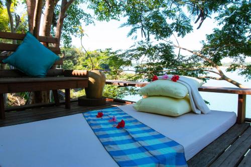 Una cama en una terraza con pájaros. en Mekong Bird Resort & Hotel, en Stœ̆ng Trêng