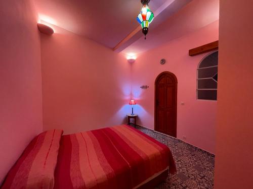 a bedroom with a red bed and a lamp at Dar Fatima in Chefchaouene