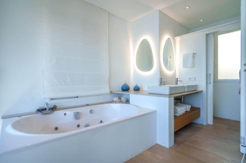 a white bathroom with a tub and two mirrors at Penthouse La Victoria in Cielo de Bonaire 