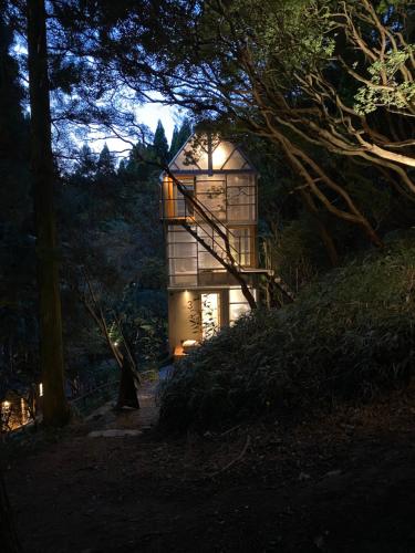 a glass house with a staircase in a forest at night at ThinkStay Mt.(シンクステイ・マウンテン) in Mikagechō