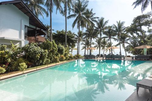 a swimming pool at a resort with palm trees at Siargao Island Villas in General Luna
