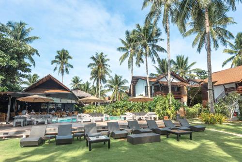 a resort with a pool and chairs and palm trees at Siargao Island Villas in General Luna