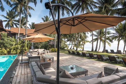 a patio with chairs and an umbrella next to a pool at Siargao Island Villas in General Luna