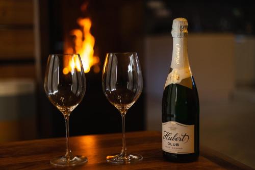 a bottle of champagne and two wine glasses on a table at Chaty Kukana a Kuku in Vysoké Tatry