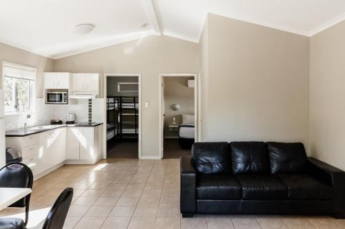 a living room with a black couch and a kitchen at BIG4 Breeze Holiday Parks - Katherine in Katherine