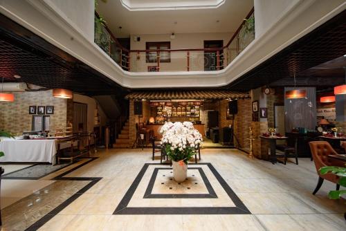 - une salle à manger avec un vase de fleurs au sol dans l'établissement Bonjour D'An Nam Hotel, à Hanoï