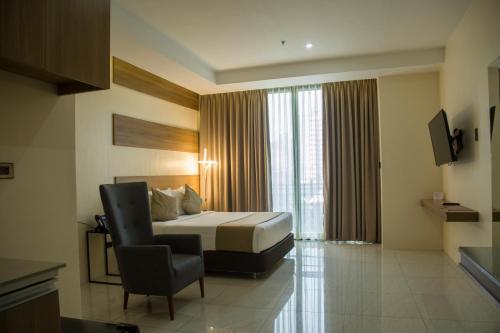 a hotel room with a bed and a chair at Eastland Hotel And Residences in Cebu City