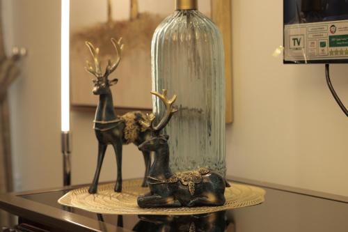eine Hirschstatue auf einem Tisch neben einer Vase in der Unterkunft PTR 3001-Lovely 1 Bedroom in Paramount Midtown in Dubai