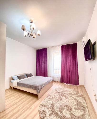 a bedroom with a bed and purple curtains at Expo residence in Taldykolʼ