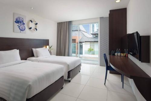 een hotelkamer met 2 bedden en een televisie bij Rodina Beach Hotel in Jomtien Beach
