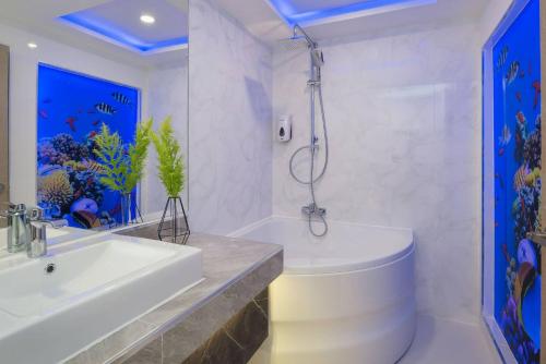 een badkamer met een wastafel, een bad en een douche bij Rodina Beach Hotel in Jomtien Beach