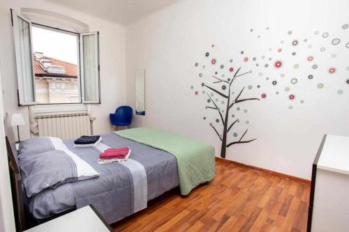 a bedroom with a bed and a tree on the wall at HOME 41 con vista mare in Trieste