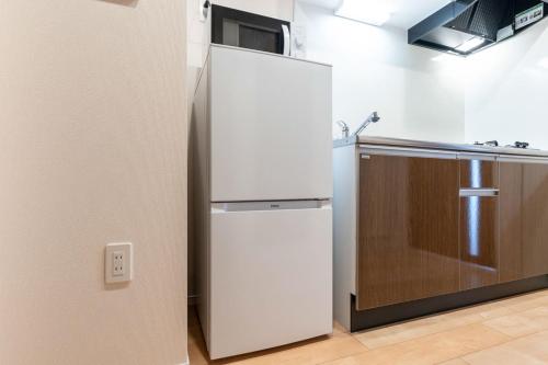 a white refrigerator in a kitchen next to a sink at Crest Court Kagurazaka in Tokyo