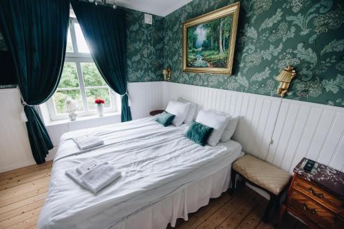ein Schlafzimmer mit einem großen weißen Bett mit grüner Tapete in der Unterkunft Mjällbyhus Pensionat & Stugby in Sölvesborg