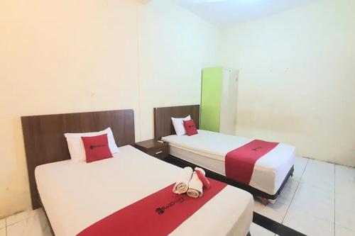 twee bedden in een hotelkamer met een handtas erop bij RedDoorz near Universitas PGRI Kanjuruhan in Gadang