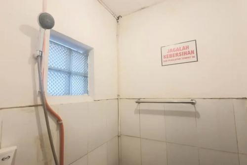 a bathroom with a shower with a window and a sign at RedDoorz near Universitas PGRI Kanjuruhan in Gadang