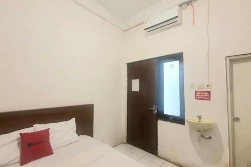 a bedroom with a bed with a red pillow and a window at RedDoorz near Universitas PGRI Kanjuruhan in Gadang