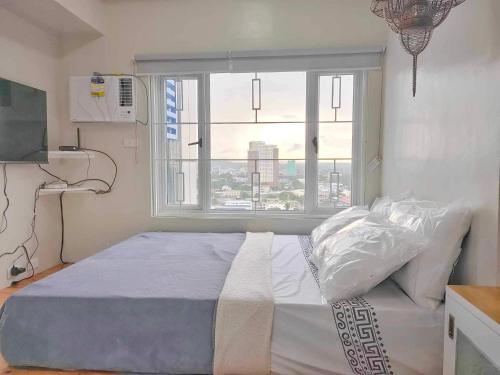 ein Schlafzimmer mit einem Bett und einem großen Fenster in der Unterkunft Best Condo Studio within Limketkai Center in Cagayan de Oro