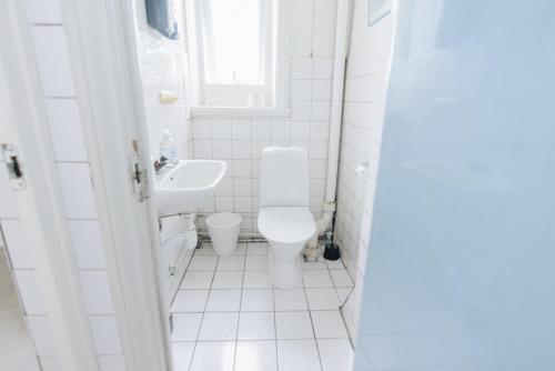 a white bathroom with a toilet and a sink at Mjällbyhus Pensionat & Stugby in Sölvesborg