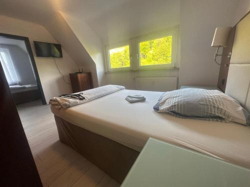 a large bed in a room with two windows at Monteur- und Urlaubsunterkünfte in Altena