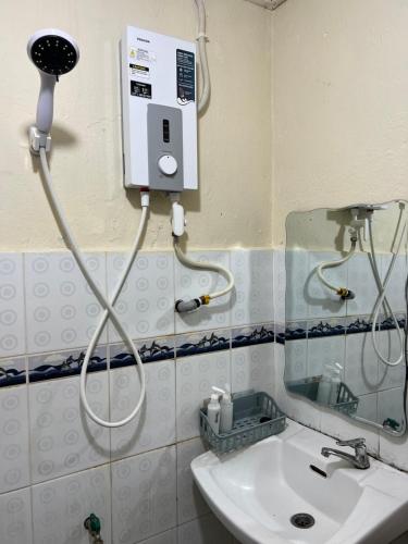 ein Bad mit einem Duschkopf und einem Waschbecken in der Unterkunft JL Homestay Taman Pertama Satu in Lahad Datu