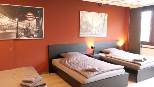2 camas en una habitación con paredes de color naranja en Bett + Fitness en Kassel