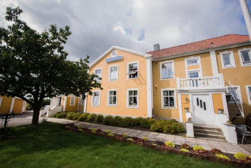 un gran edificio amarillo con un árbol en el patio en Mjällbyhus Pensionat & Stugby en Sölvesborg