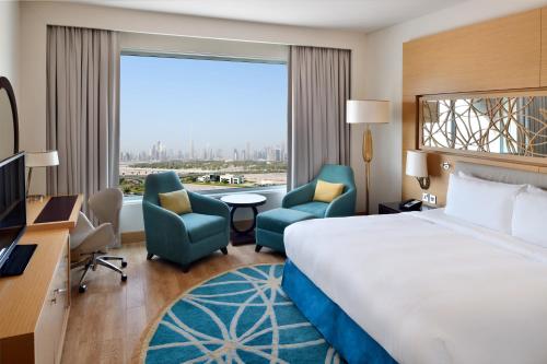 a hotel room with a bed and chairs and a large window at Marriott Hotel Al Jaddaf, Dubai in Dubai