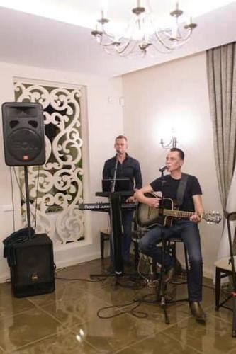 two men playing instruments in a room with a microphone at Villa Orchidea in Šakiai