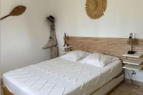 een slaapkamer met een wit bed en een houten hoofdeinde bij "Villa Les Didi" Jacuzzi, proche de la mer in Solaro