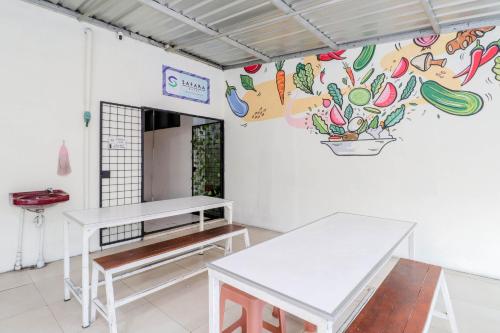 um quarto com duas mesas e um mural na parede em Hotel Safara Yogyakarta em Yogyakarta