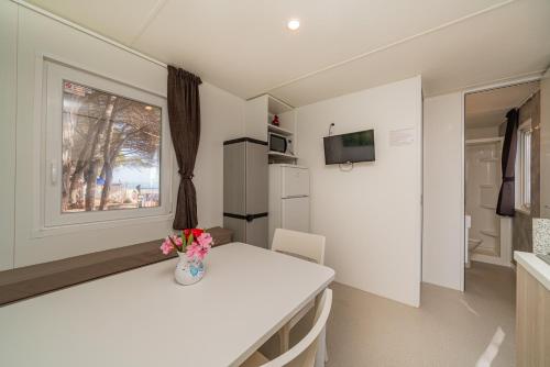 a white kitchen with a table and a vase with flowers at Camping&Village Le Cernie in Lotzorai
