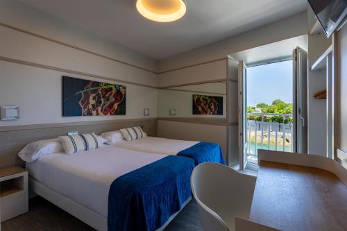 a hotel room with two beds and a balcony at Hotel&Spa El Puerto in Mundaka