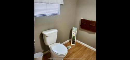 a bathroom with a white toilet and a wooden floor at Jeans Place in Northfork