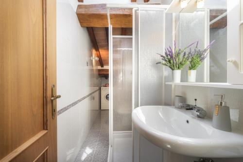 ein weißes Badezimmer mit einem Waschbecken und einem Spiegel in der Unterkunft Casa Giulia, centro storico di Cortona con A/C! in Cortona