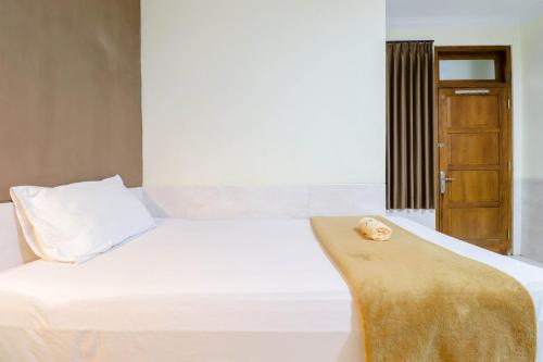 a bedroom with a white bed and a wooden door at Hotel Safara Yogyakarta in Yogyakarta