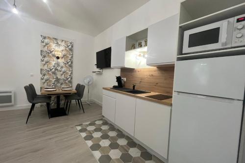 une cuisine avec des placards blancs et une table avec une salle à manger dans l'établissement El Castillo - Tournon-sur-Rhône, à Tournon-sur-Rhône