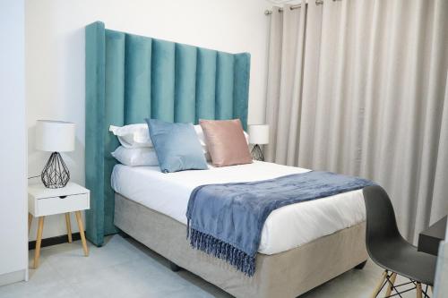 ヨハネスブルグにあるMedon Luxury Suites with power back up Bryanston Sandtonのベッドルーム1室(青いヘッドボード付きのベッド1台付)